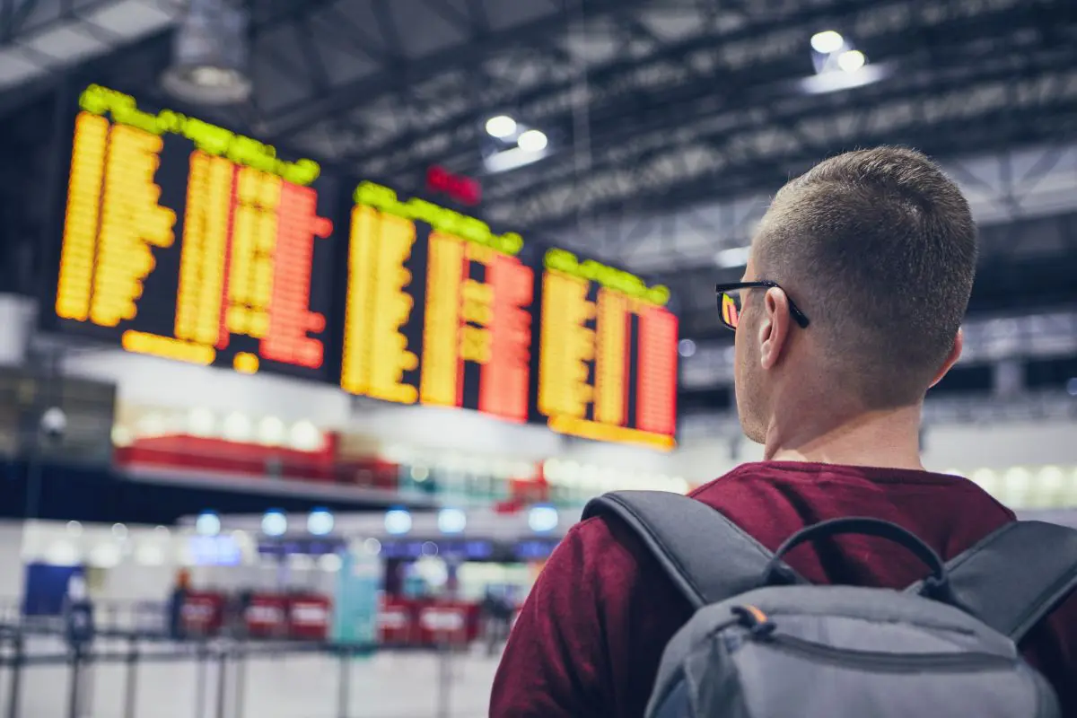 ragazzo in aeroporto controlla tabellone voli