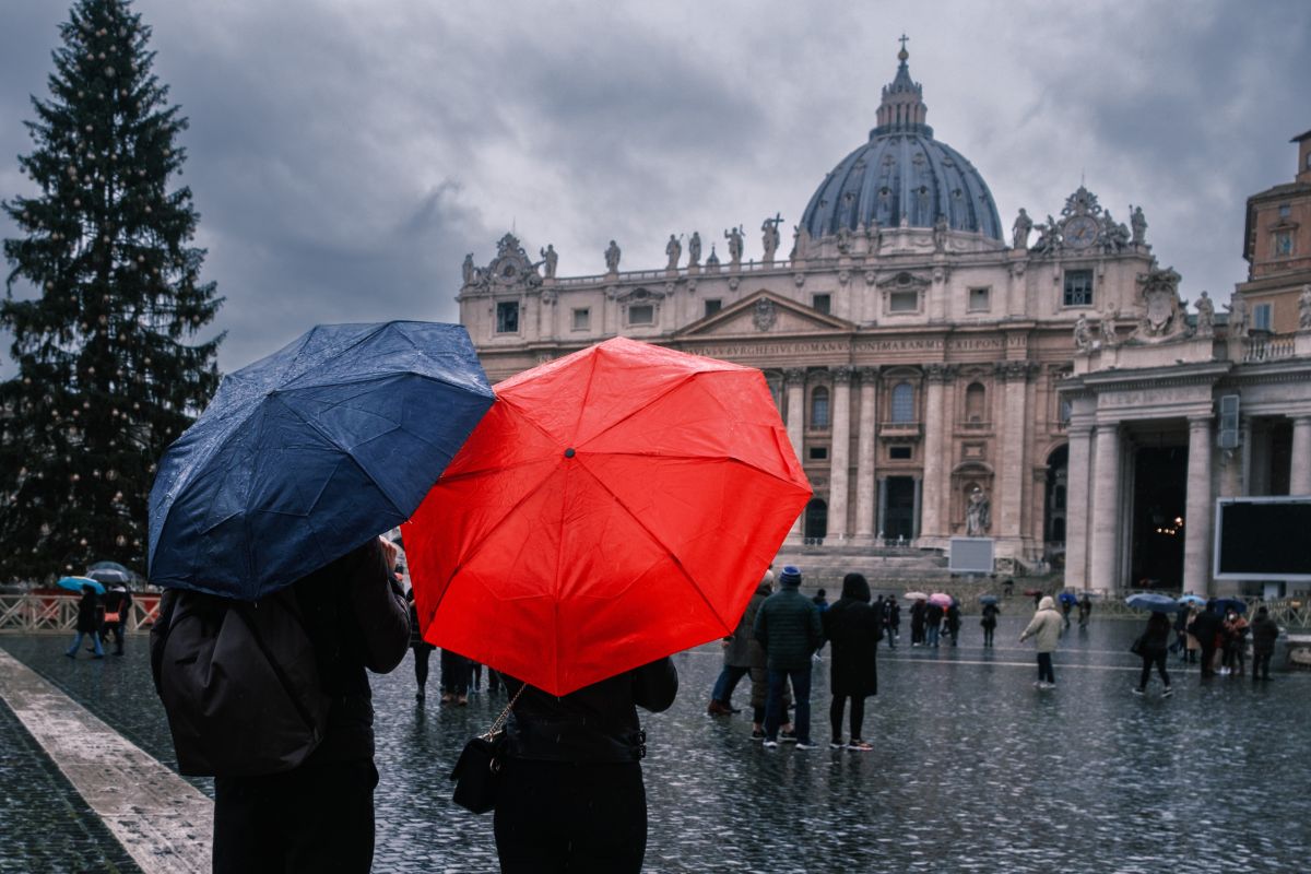 gente con ombrello che cammina vicino alla basilica di san pietro in vaticano durante una giornata di pioggia