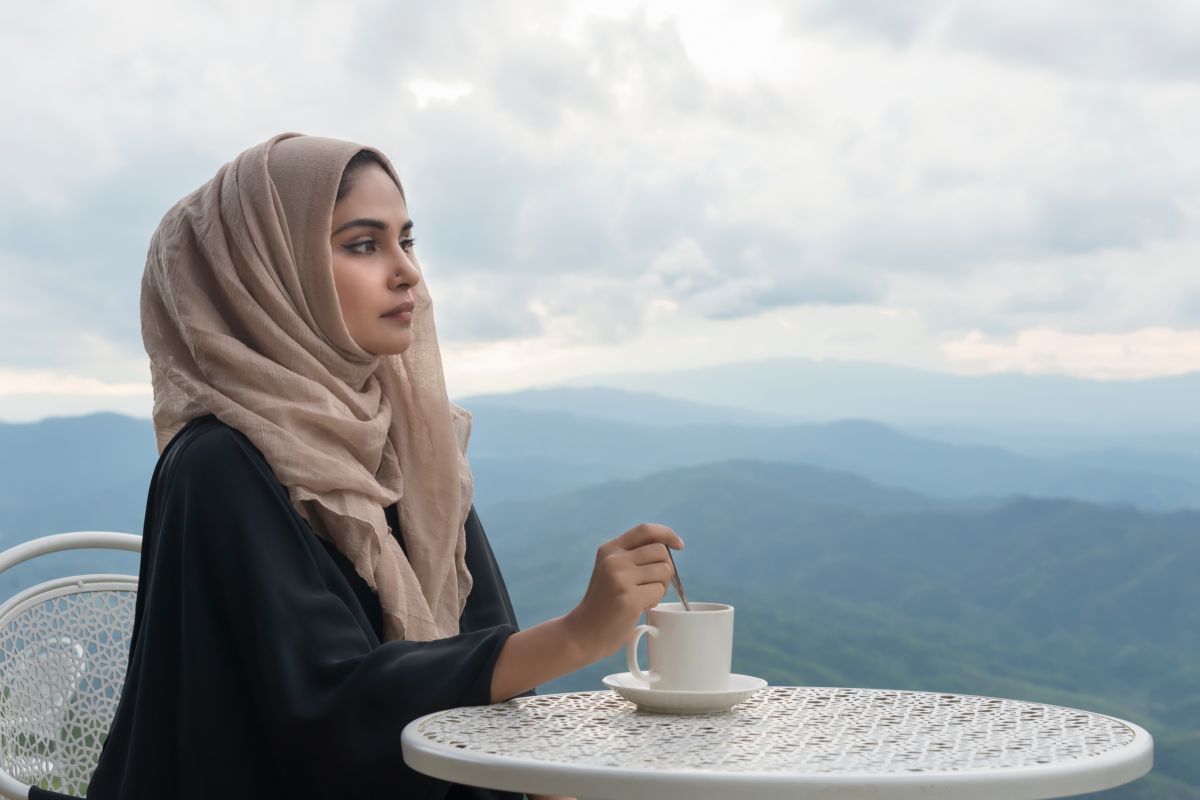 donna araba con hijab, velo, prende il caffè al bar