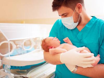 medico uomo tiene neonato in braccio