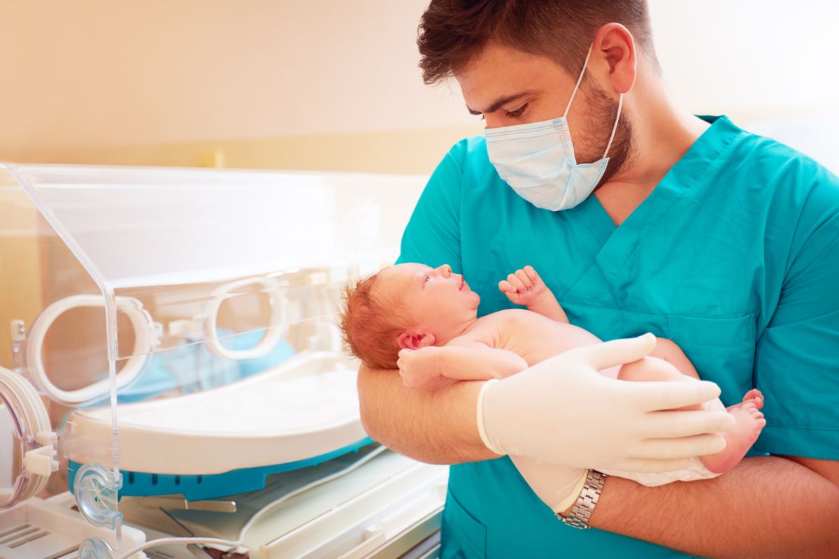 medico uomo tiene neonato in braccio
