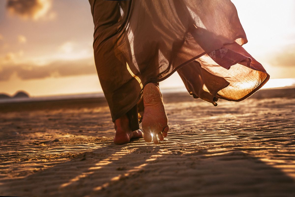 donna cammina a piedi nudi sulla sabbia in spiaggia