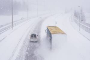 camion e auto viaggiano con la neve in superstrada