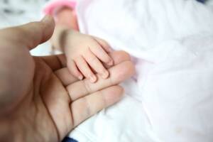 bambino neonato con mano adulta