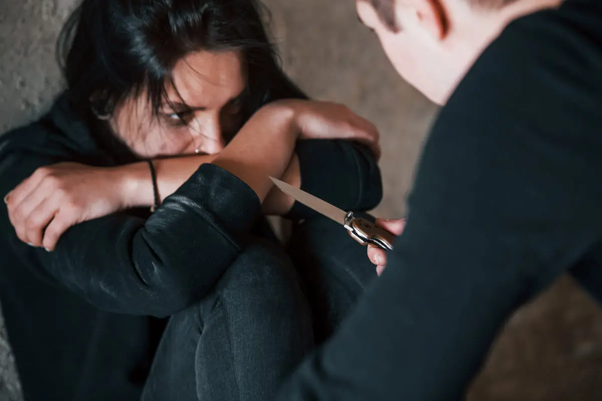 donna impaurita aggredita da un uomo con un coltello