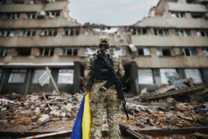 Soldato ucraino guarda il palazzo distrutto