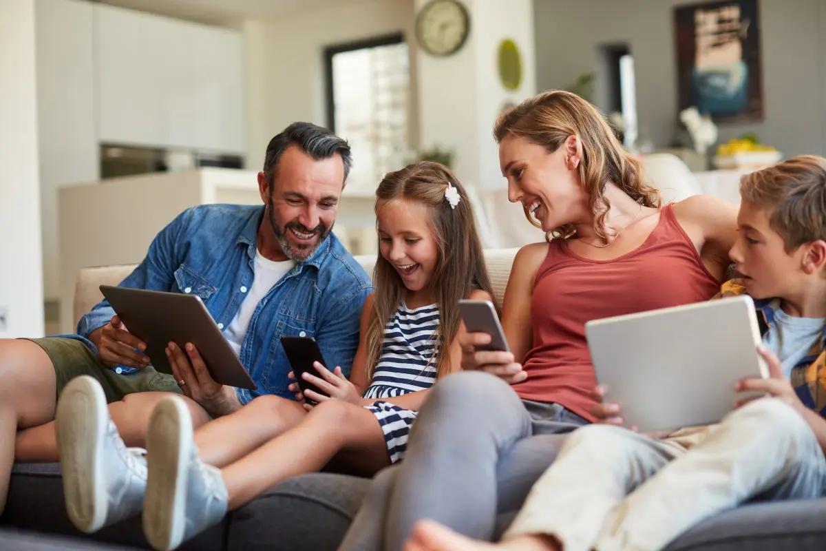 Una famiglia sul divano con telefoni e ipad