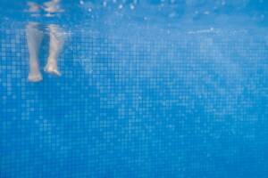 gambe di una persona in piscina sott'acqua