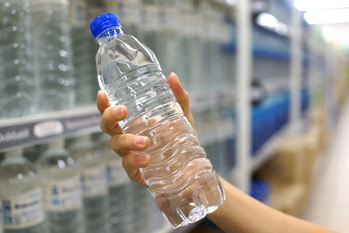 Persona che tiene in mano una bottiglia d'acqua di plastica