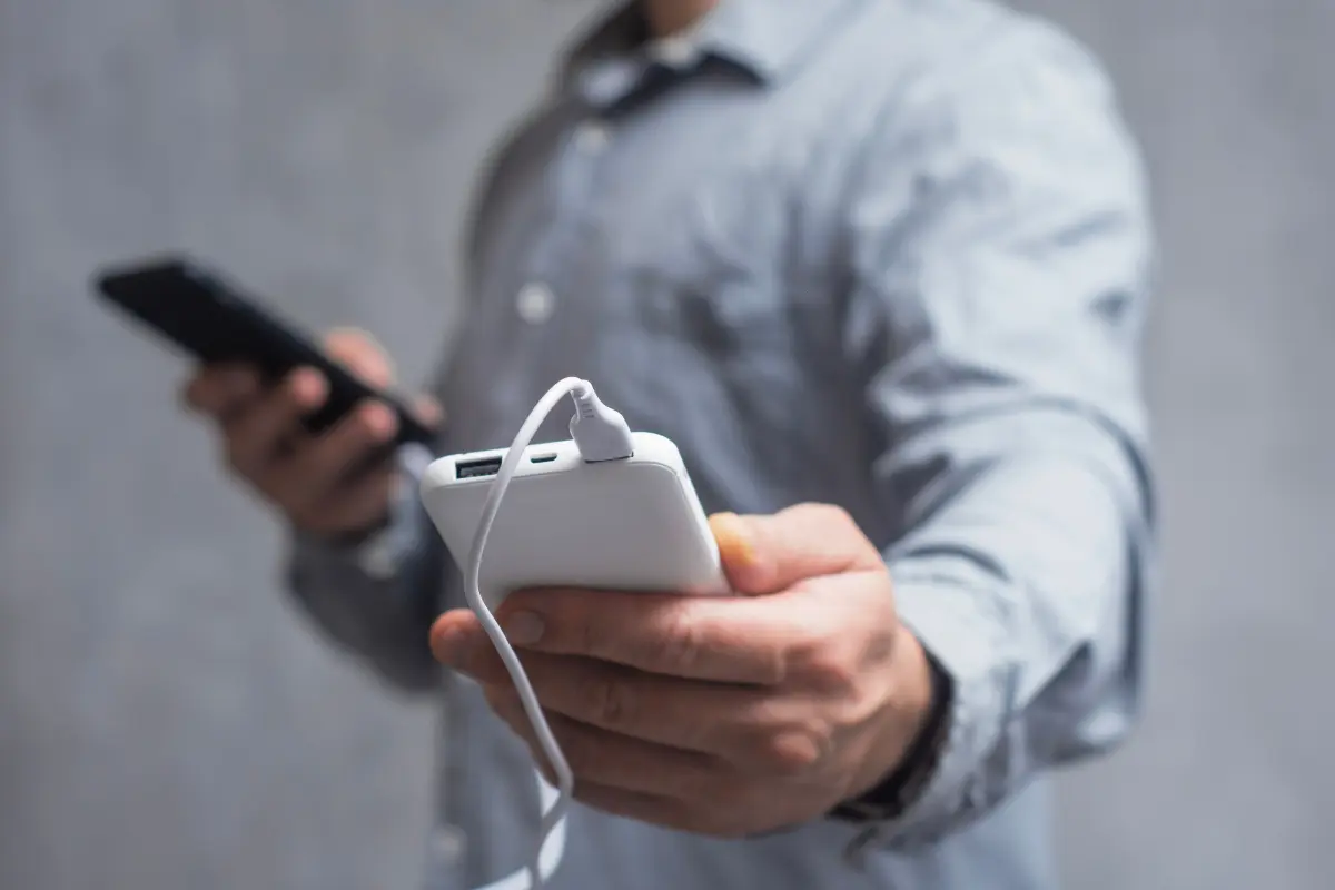 Un uomo con un cellulare e un powebank in mano 