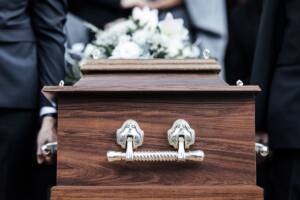Cerimonia funebre con bara e fiori bianchi
