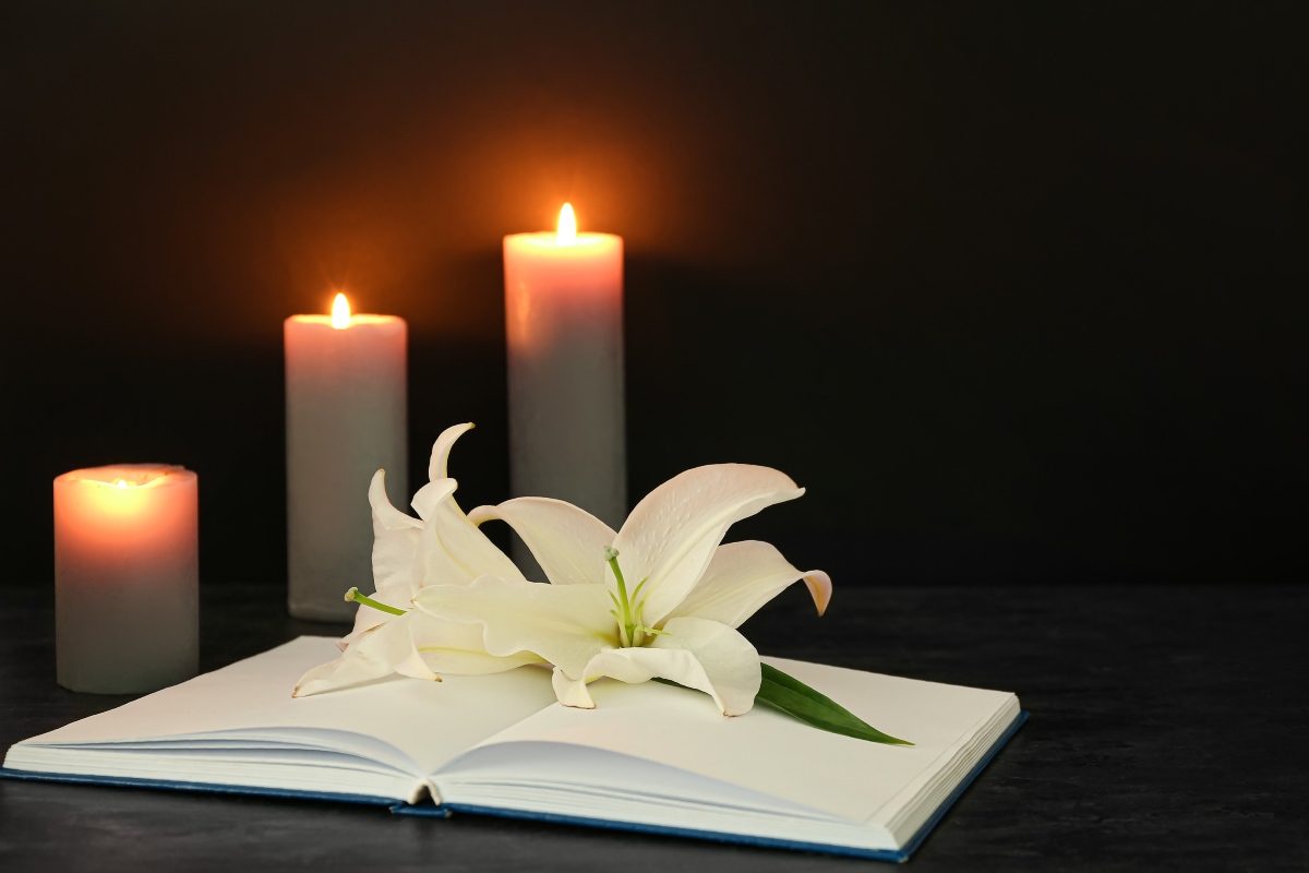 Momento di lutto con gigli, libro e candele accese