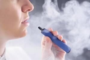 Una persona produce del fumo mentre utilizza una sigaretta elettronica.