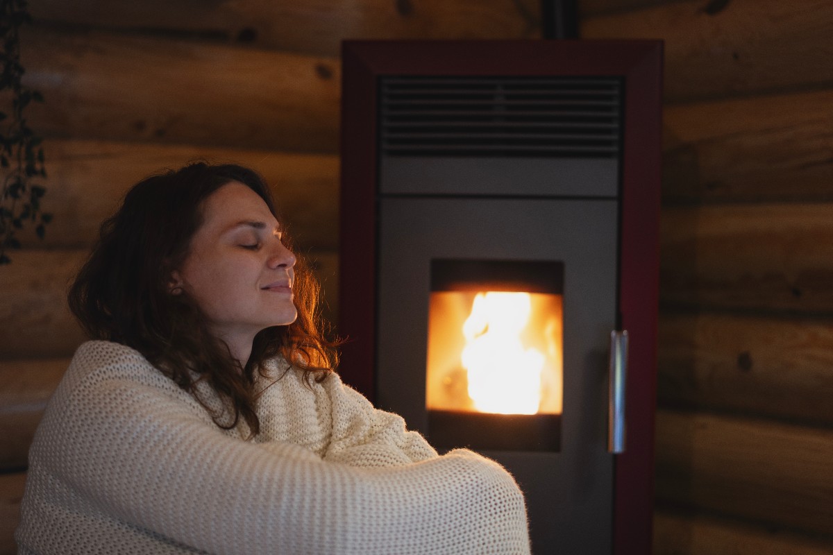 Donna si riscalda con stufa a pellet