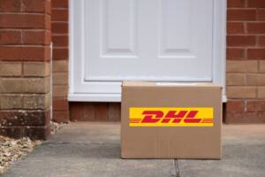 Pacco DHL appena consegnato, posizionato davanti alla porta d’ingresso di un’abitazione.