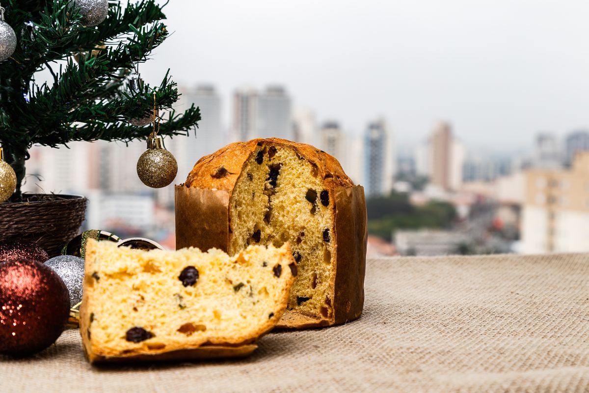 un panettone e una fetta con accanto un albero di Natale