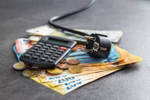 Costo dell'energia: banconote con sopra calcolatrice e spina elettrica.