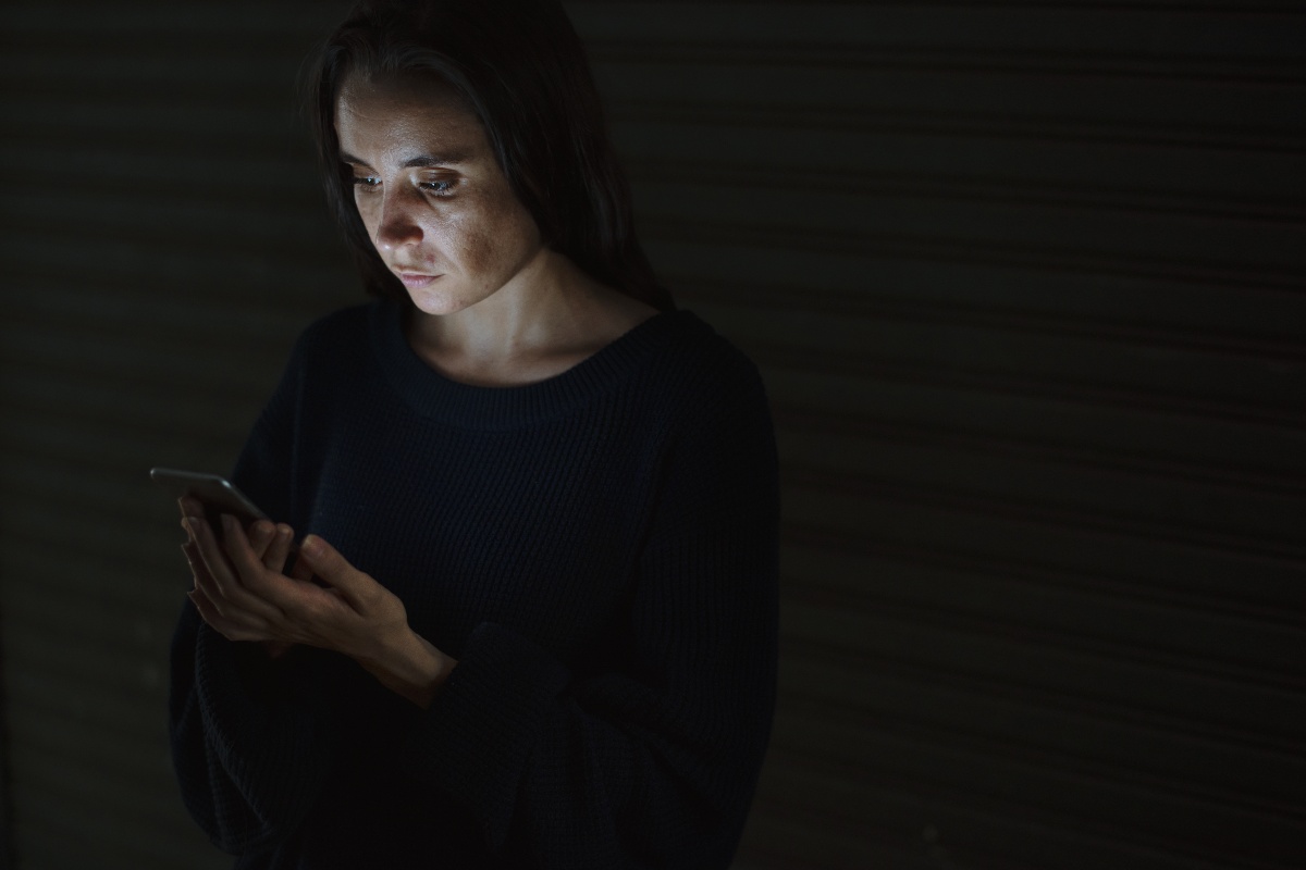 una donna usa un cellulare nell'ombra