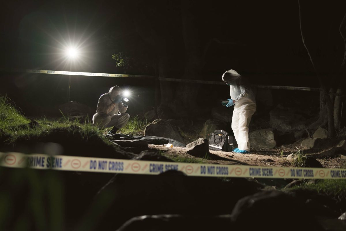 due uomini delle scientifica sulla scena di un crimine di notte