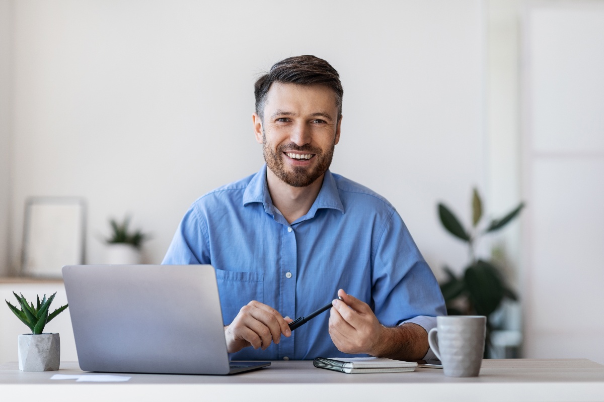 Atmosfera positiva in ufficio: un ragazzo sorridente mentre lavora al computer nel suo ambiente professionale.