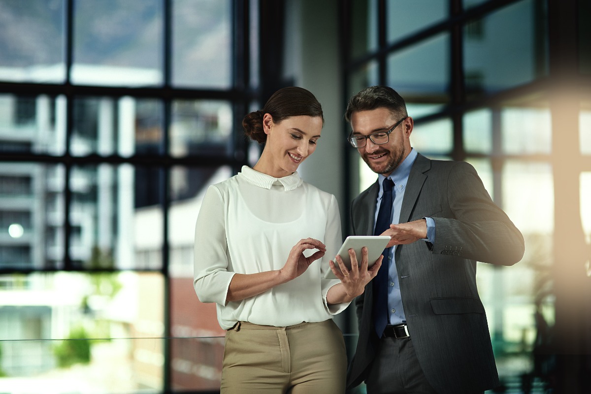 Due colleghi mentre consultano un tablet e si scambiano pareri all'interno dell'ufficio.