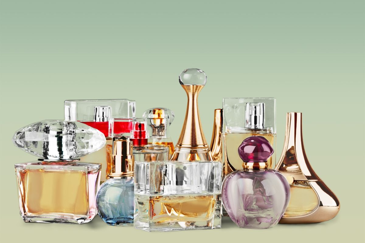 Assortimento profumi: flaconi di varie dimensioni e colori su sfondo verde chiaro.