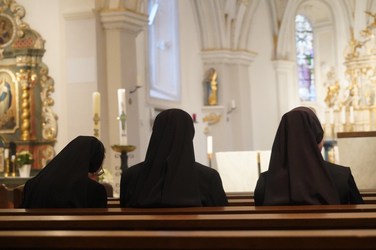 tre suore sedute all'interno di una chiesa