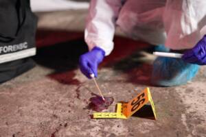 polizia scientifica raccoglie prove organiche a terra in una scena del crimine