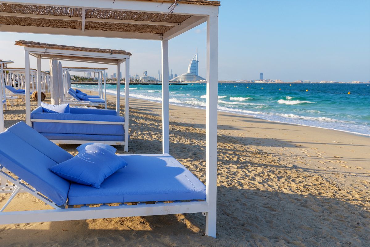 Spiaggia attrezzata a Dubai con lettini imbottiti e materassi blu.