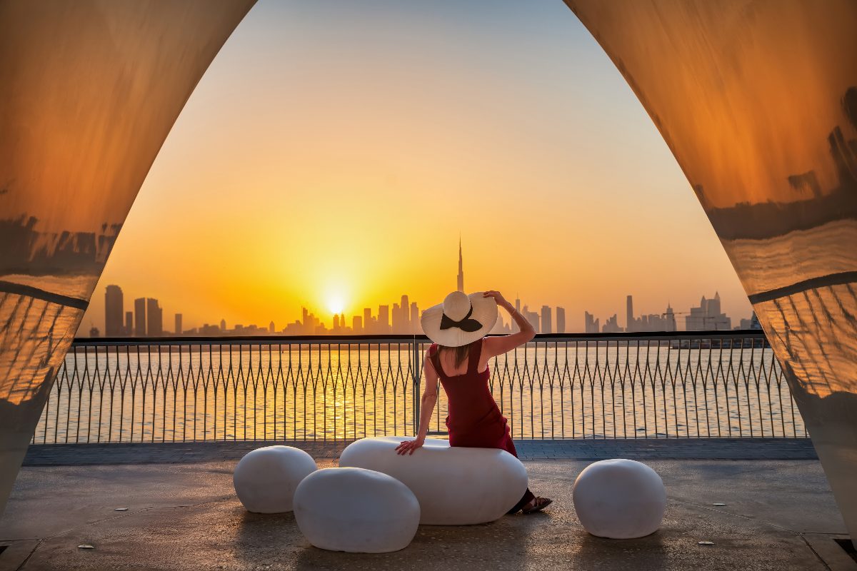 Turista a Dubai con lo skyline della città sullo sfondo al tramonto.