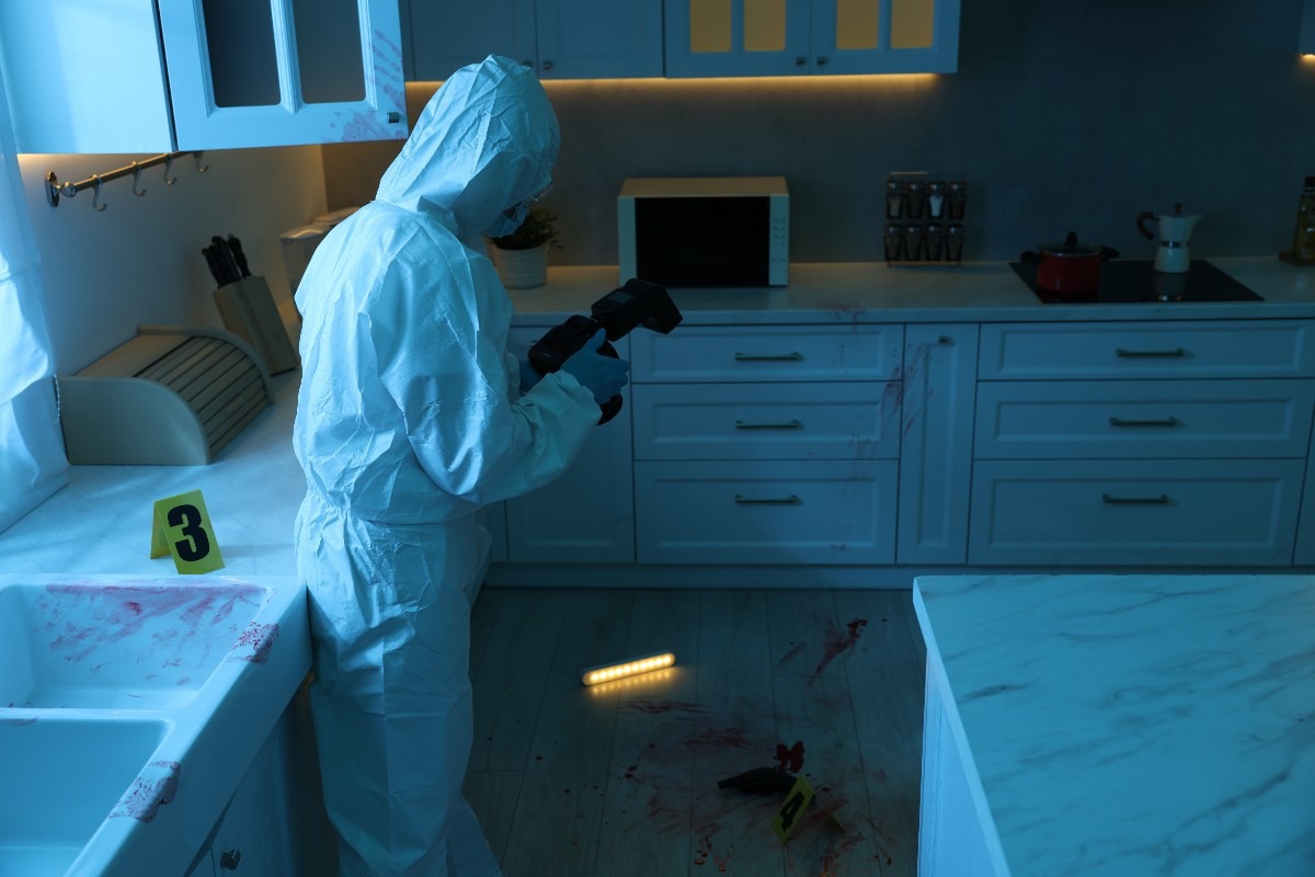scena del crimine di una cucina con un uomo della scientifica