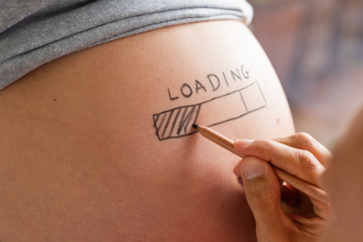 Una donna incinta con il disegno della barra di caricamento "loading" sul pancione.