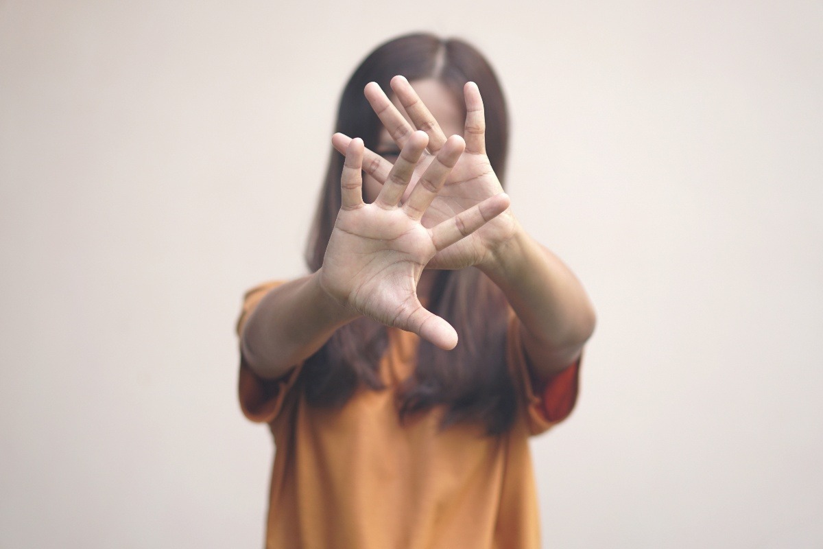 una ragazzina che chiede di fermare la violenza sui bambini con le mani che coprono il volto