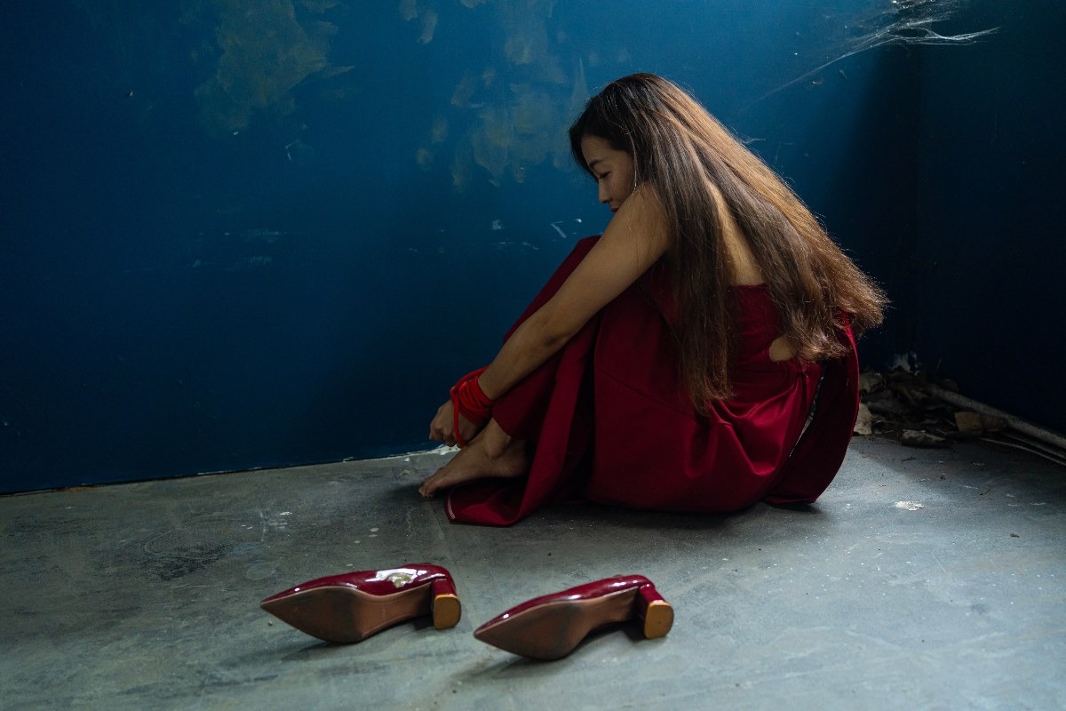 una ragazza rapita e spaventata con un abito rosso e due scarpe rosse