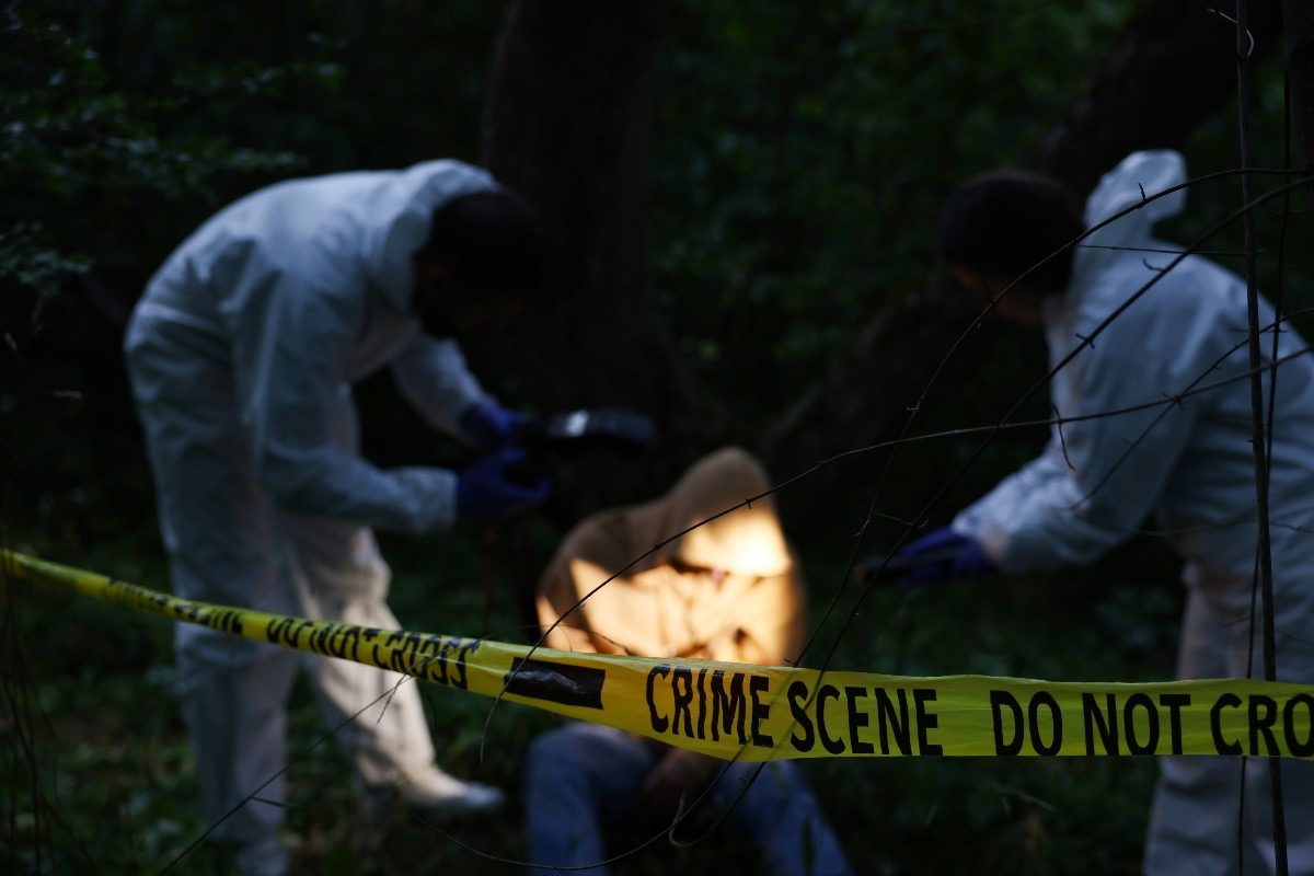 la scientifica analizza la scena del crimine con un cadavere