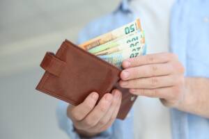 un uomo apre il portafoglio con delle banconote in euro