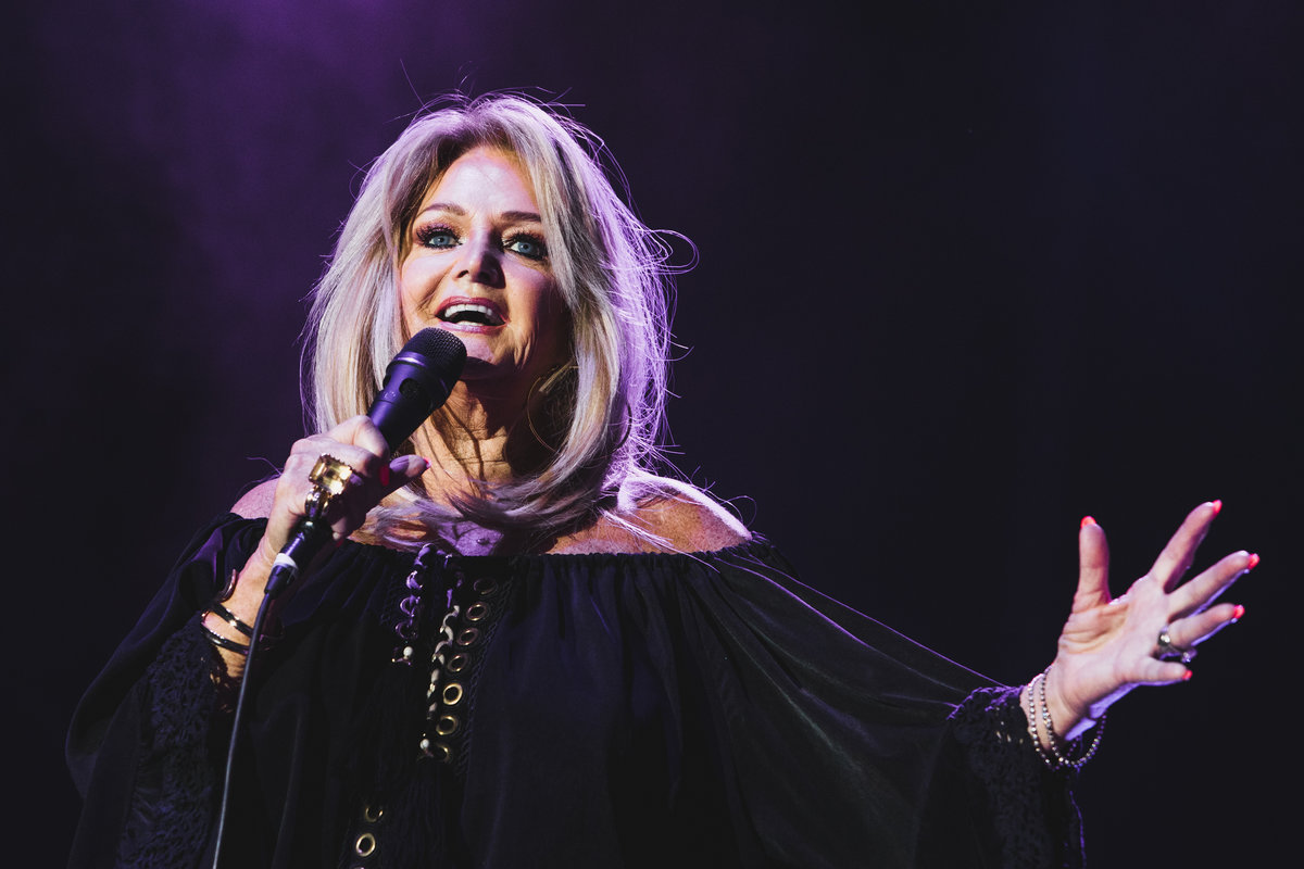 la cantante Bonnie Tyler canta sul palco con il microfono e con la mano aperta