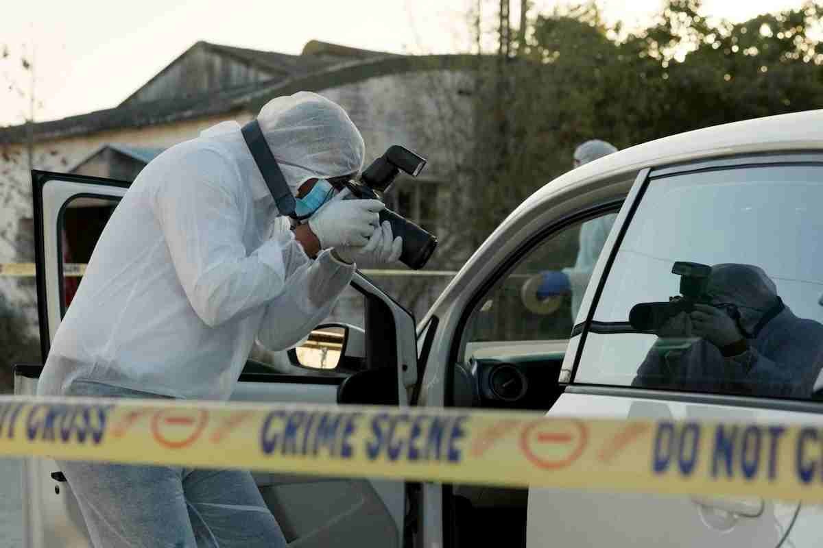 agenti della scientifica che analizzando una scena del crimine scattando delle foto dentro un'auto