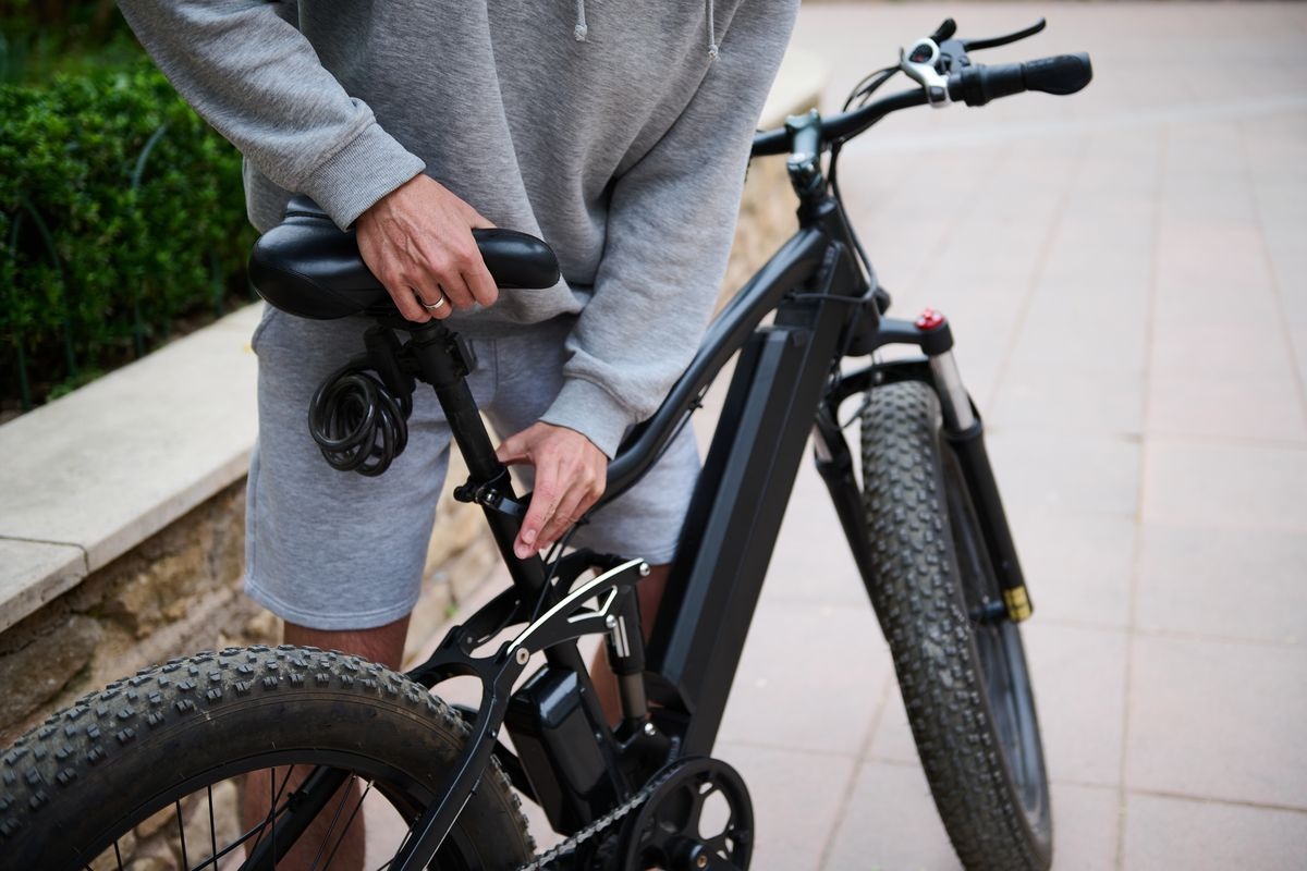 un ciclista con una e-bike che sistema il sellino
